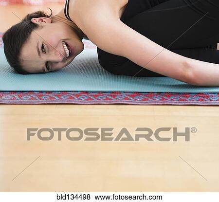 Stock Photo - Caucasian woman smiling on yoga mat. Fotosearch
