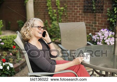 Stock Image - Caucasian woman talking on cell phone outdoors. Fotosearch