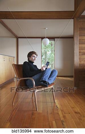 Caucasian woman using cell phone in armchair View Large Photo Image Picture - Caucasian woman using cell phone in armchair. Fotosearch
