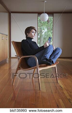 Caucasian woman using cell phone in armchair View Large Photo Image Stock Image - Caucasian woman using cell phone in armchair. Fotosearch