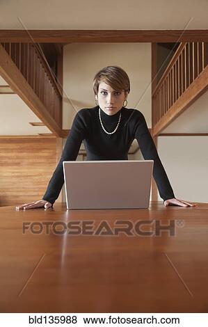 Caucasian woman using laptop on table View Large Photo Image Stock Photo - Caucasian woman using laptop on table. Fotosearch