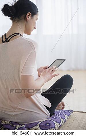 Stock Image - Caucasian woman using tablet computer in living room. Fotosearch