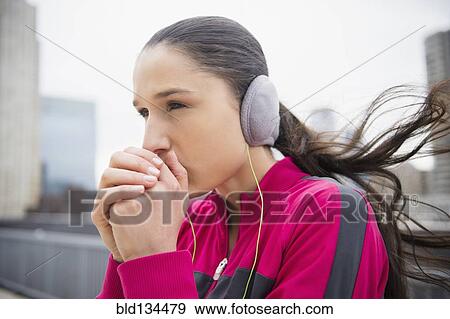 Stock Photo - Caucasian woman warming hands in city. Fotosearch