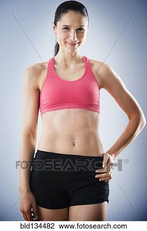 Stock Image - Caucasian woman with bare stomach wearing sports clothing. Fotosearch