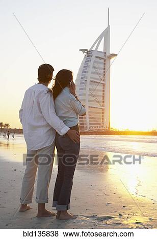 Couple admiring monument on beach, Dubai, United Arab Emirates View Large Photo Image Stock Photo - Couple admiring monument on beach, Dubai, United Arab Emirates. Fotosearch