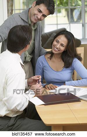 Couple and businessman examining papers View Large Photo Image Stock Photo - Couple and businessman examining papers. Fotosearch