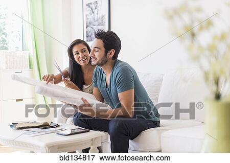 Couple examining blueprints in living room View Large Photo Image Stock Photo - Couple examining blueprints in living room. Fotosearch