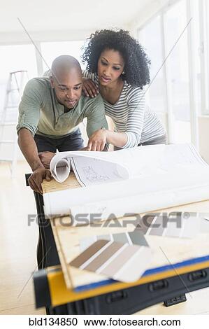 Stock Image - Couple examining blueprints of new home. Fotosearch