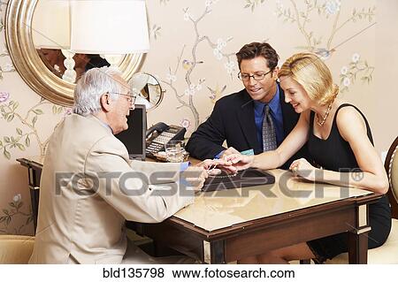 Couple examining jewelry with salesman View Large Photo Image Stock Photo - Couple examining jewelry with salesman. Fotosearch