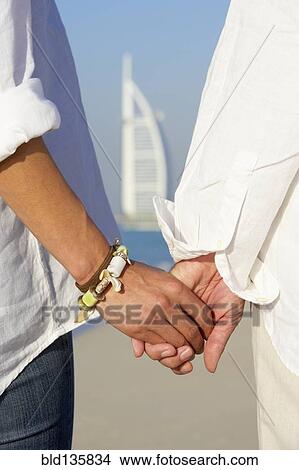 Couple holding hands on beach, Dubai, United Arab Emirates View Large Photo Image Picture - Couple holding hands on beach, Dubai, United Arab Emirates. Fotosearch