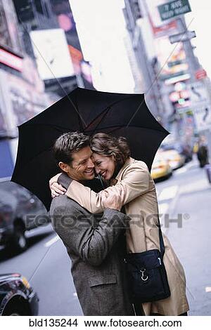 Picture - Couple huddled under umbrella on city street. Fotosearch