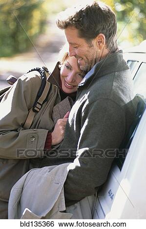 Stock Photograph - Couple hugging by car. Fotosearch