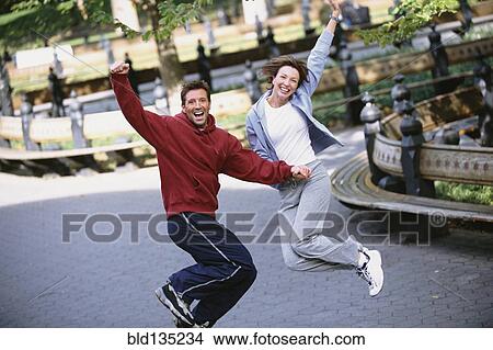 Couple jumping for joy in urban park View Large Photo Image Picture - Couple jumping for joy in urban park. Fotosearch