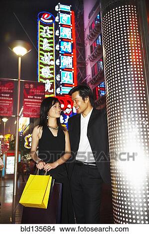 Couple on city street lit up at night, Shanghai, China View Large Photo Image Picture - Couple on city street lit up at night, Shanghai, China. Fotosearch