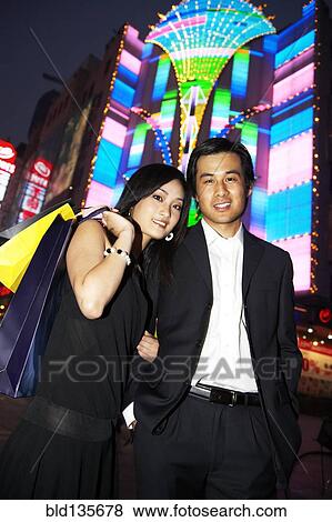 Couple on city street lit up at night, Shanghai, China View Large Photo Image Stock Photo - Couple on city street lit up at night, Shanghai, China. Fotosearch