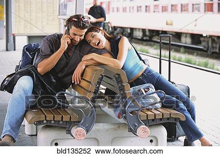 Stock Image - Couple relaxing at train station. Fotosearch