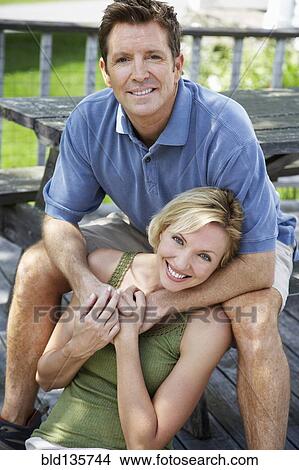 Couple relaxing on wooden patio View Large Photo Image Picture - Couple relaxing on wooden patio. Fotosearch