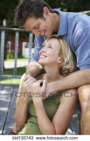 Stock Image - Couple relaxing on wooden patio. Fotosearch