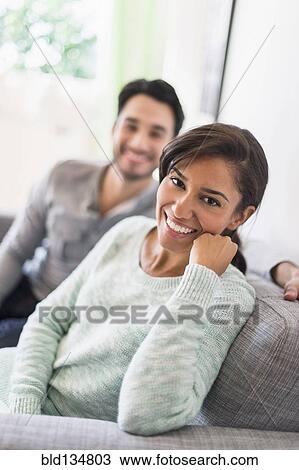 Stock Image - Couple relaxing together on sofa. Fotosearch