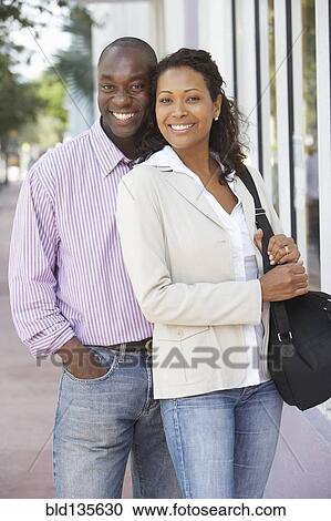 Couple smiling together on city street View Large Photo Image Stock Image - Couple smiling together on city street. Fotosearch