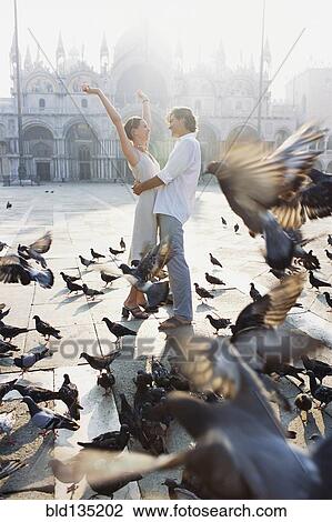 Couple surrounded by pigeons in St. Mark's Square, Venice, Veneto, Italy View Large Photo Image Stock Image - Couple surrounded by pigeons in St. Mark's Square, Venice, Veneto, Italy. Fotosearch