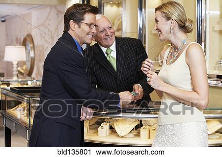 Stock Image - Couple talking to salesman in jewelry store. Fotosearch