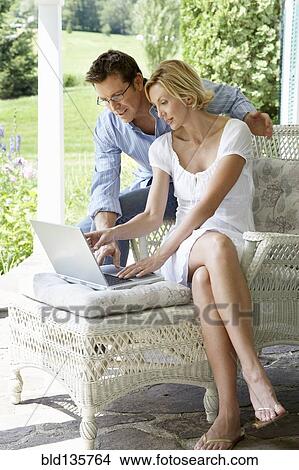 Couple using laptop together on patio View Large Photo Image Picture - Couple using laptop together on patio. Fotosearch