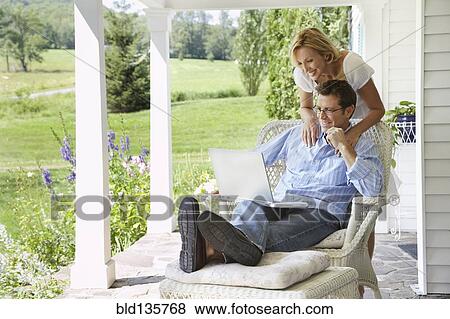 Couple using laptop together on patio View Large Photo Image Stock Photo - Couple using laptop together on patio. Fotosearch