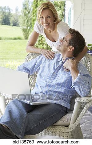 Stock Photo - Couple using laptop together on patio. Fotosearch