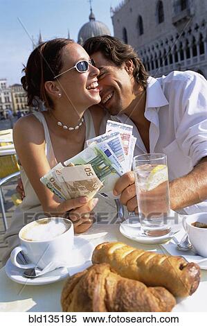Couple with wads of cash having breakfast at cafe View Large Photo Image Stock Photography - Couple with wads of cash having breakfast at cafe. Fotosearch