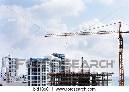 Crane extending over urban construction site View Large Photo Image Stock Image - Crane extending over urban construction site. Fotosearch