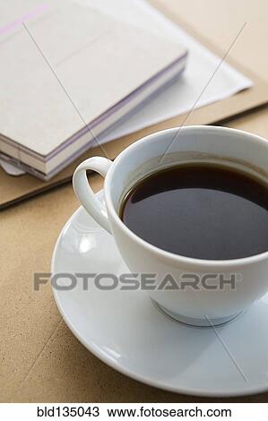 Cup of coffee on table with book View Large Photo Image Stock Image - Cup of coffee on table with book. Fotosearch