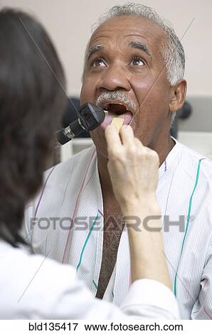 Stock Photo - Doctor checking Senior man's tongue. Fotosearch
