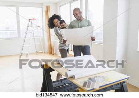 Family examining blueprints in new home View Large Photo Image Stock Photo - Family examining blueprints in new home. Fotosearch