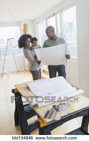 Stock Photograph - Family examining blueprints in new home. Fotosearch