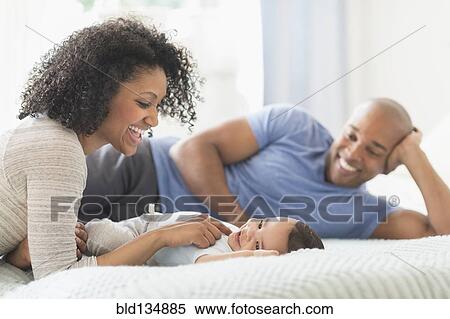 Family relaxing together on bed View Large Photo Image Stock Photography - Family relaxing together on bed. Fotosearch