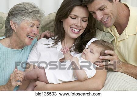Stock Image - Family relaxing together on sofa. Fotosearch