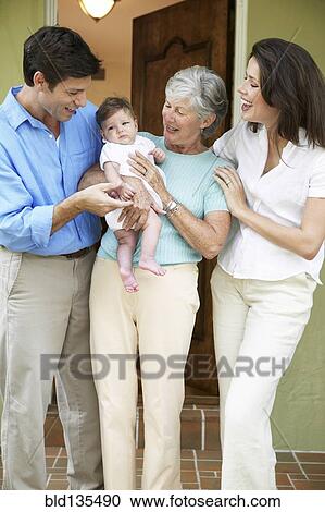 Stock Image - Family smiling together at front door. Fotosearch