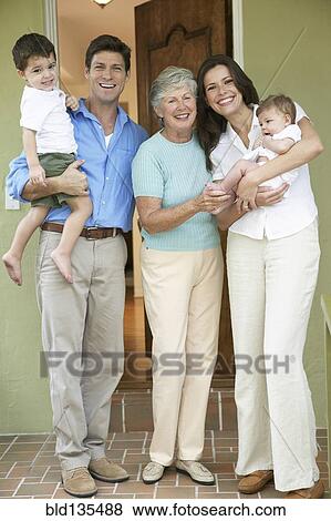 Stock Photo - Family smiling together at front door. Fotosearch