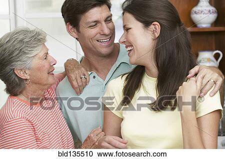 Stock Image - Family smiling together in kitchen. Fotosearch