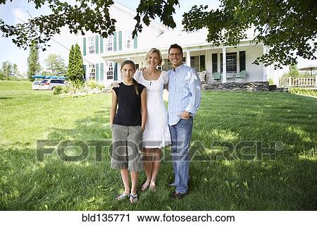 Stock Image - Family standing outside suburban house. Fotosearch