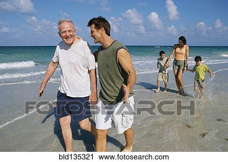 Stock Image - Family walking together on beach. Fotosearch
