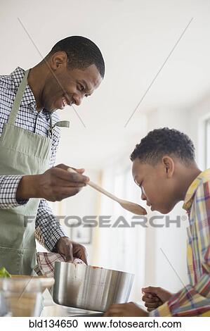 Stock Image - Father and son cooking together in kitchen. Fotosearch
