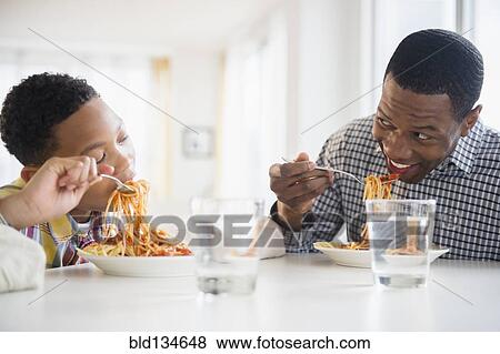 Father and son eating together at table View Large Photo Image Stock Photo - Father and son eating together at table. Fotosearch