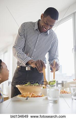 Father and son eating together at table View Large Photo Image Stock Photo - Father and son eating together at table. Fotosearch