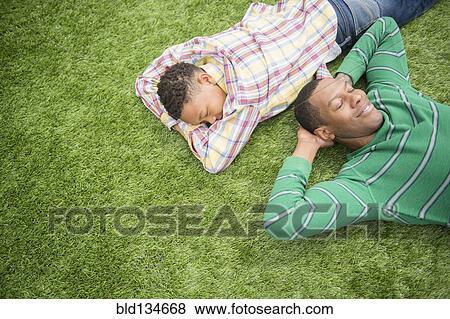Father and son relaxing in grass View Large Photo Image Stock Photo - Father and son relaxing in grass. Fotosearch