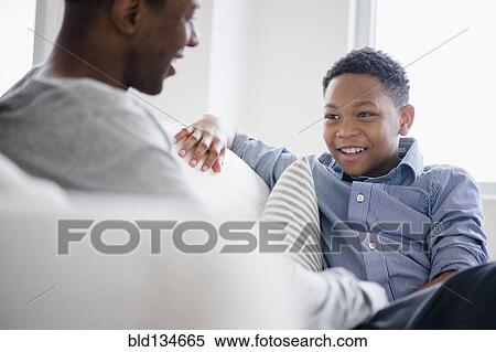 Father and son relaxing on sofa View Large Photo Image Stock Photography - Father and son relaxing on sofa. Fotosearch