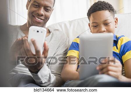 Father and son using technology together View Large Photo Image Picture - Father and son using technology together. Fotosearch
