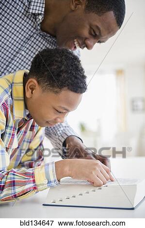 Stock Photo - Father helping son reading dictionary. Fotosearch