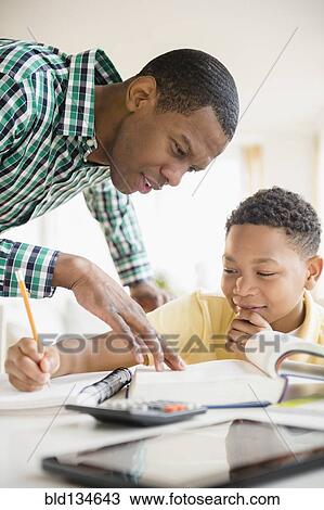 Stock Image - Father helping son with homework. Fotosearch